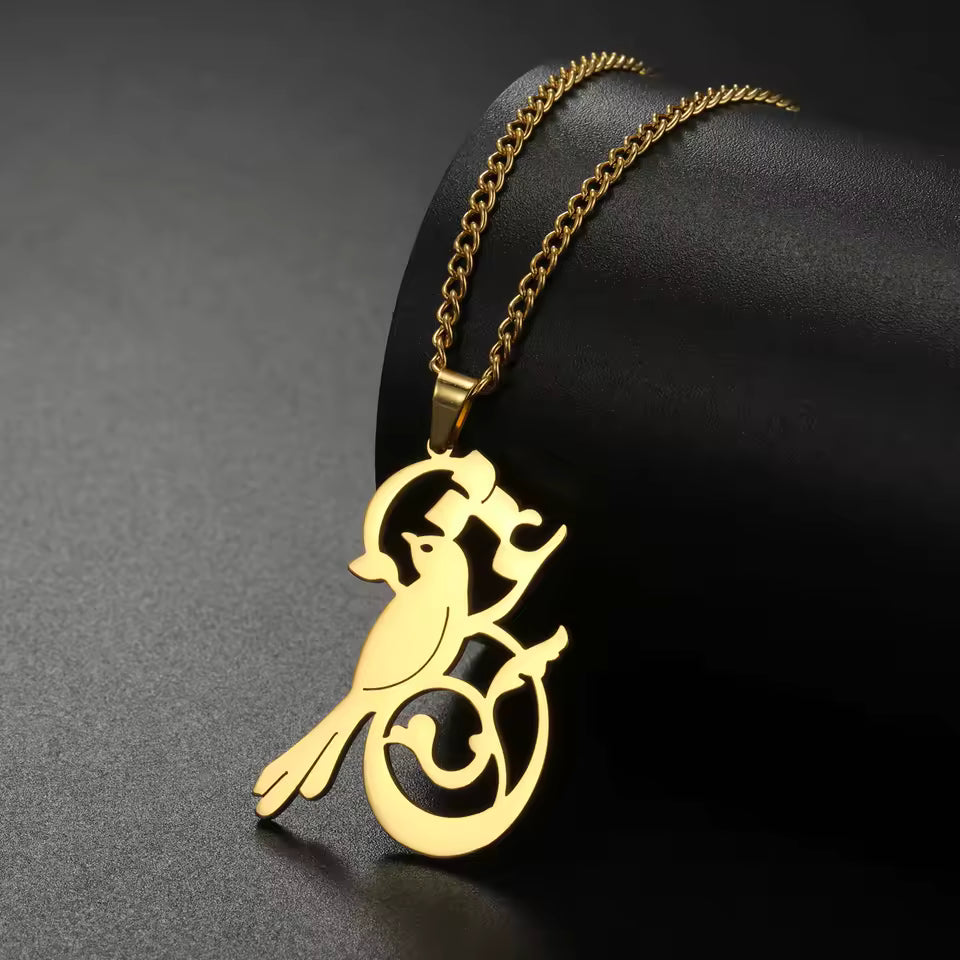 Gold bird pendant necklace on a dark background