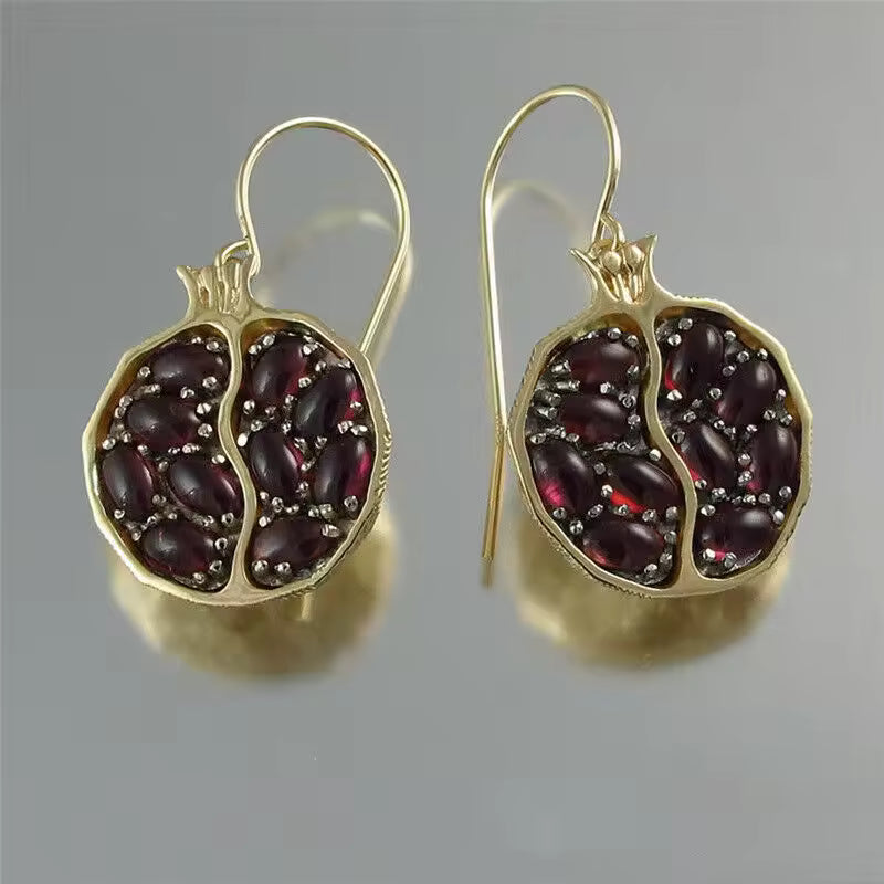 Gold earrings with red gemstones on a gray background