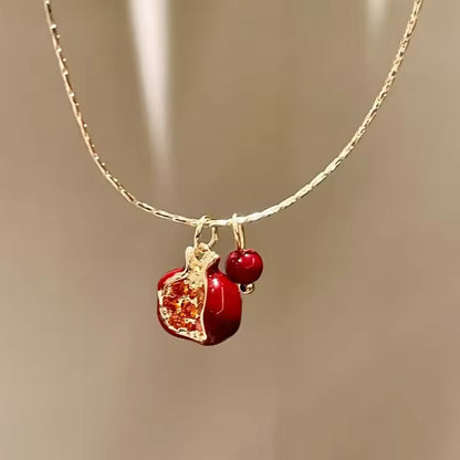 Necklace with a red pendant and gold chain on a neutral background