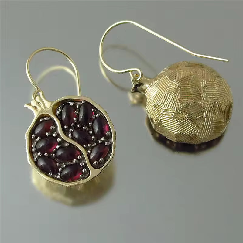 Gold earrings with gemstone details on a gray background